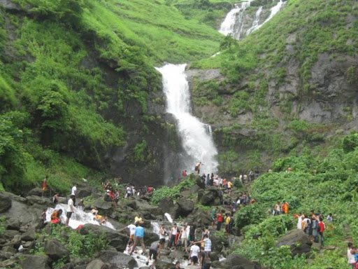 Crowd enjoying the scenic waterfall during the Ajobat Hill trek near Nashik in the monsoon season.