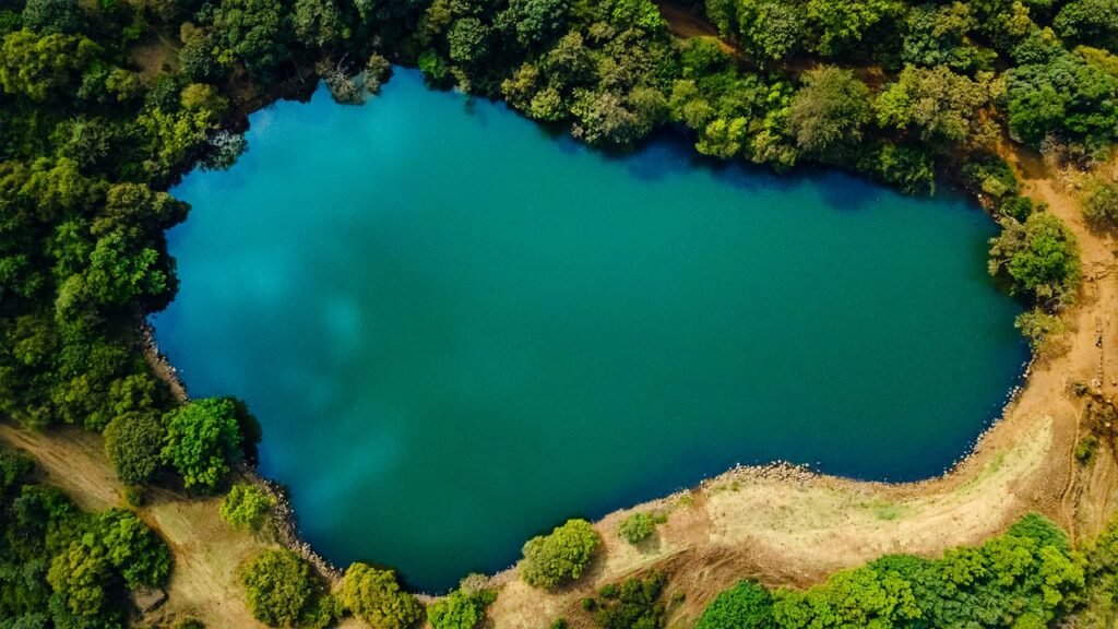 Treks Near Nashik featuring the serene heart-shaped lake at Anjaneri Trek surrounded by dense green forest.