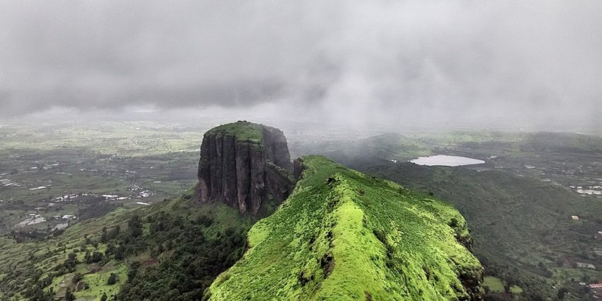 Treks Near Nashik featuring the lush green trail to Brahmagiri Fort surrounded by monsoon clouds and scenic valley views.