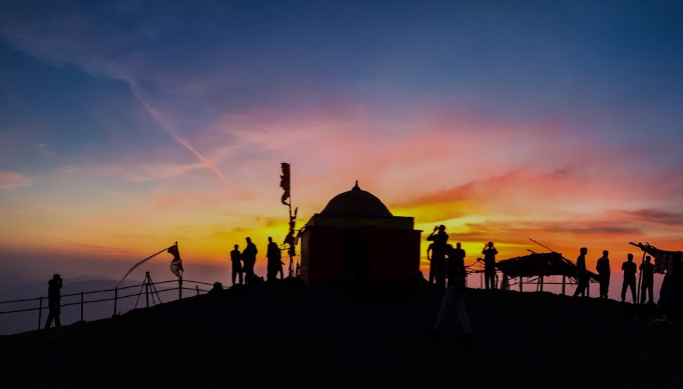 Treks Near Nashik silhouettes of people standing on a hill with a dome and a building in the background