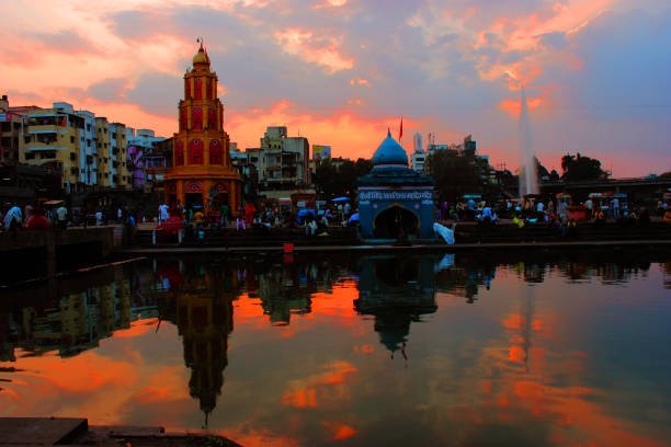 Ram-KalPath at sunset in Nashik with vibrant temple reflections on the Godavari River and a gathering of pilgrims.