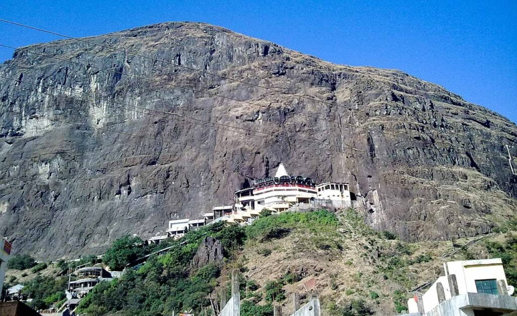 Saptashrungi Temple nestled against a steep cliff, a sacred trekking destination near Nashik.