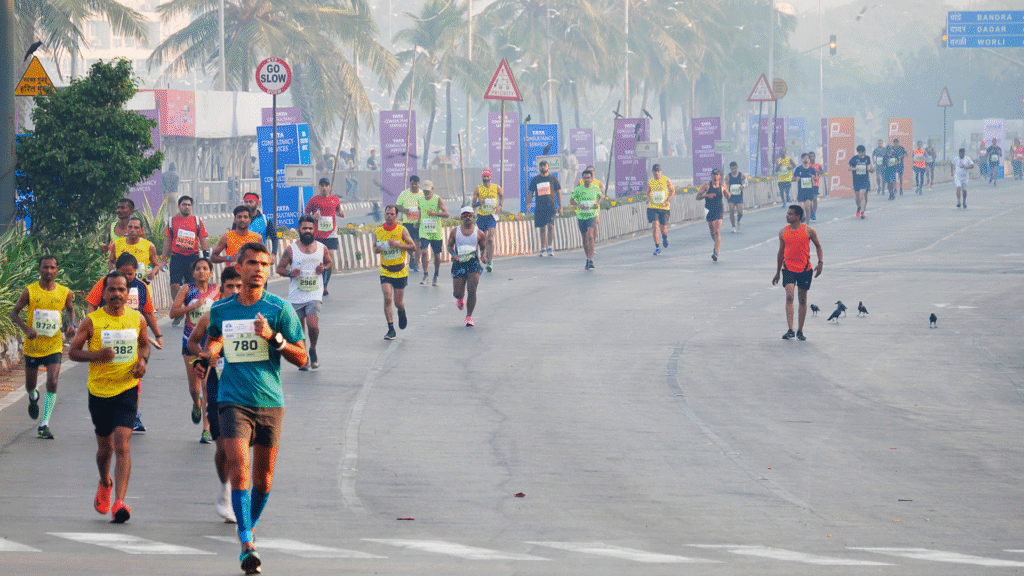 Athletes running on a foggy urban road during a large-scale event similar to Nashik Marathon 2025, showcasing diverse participants